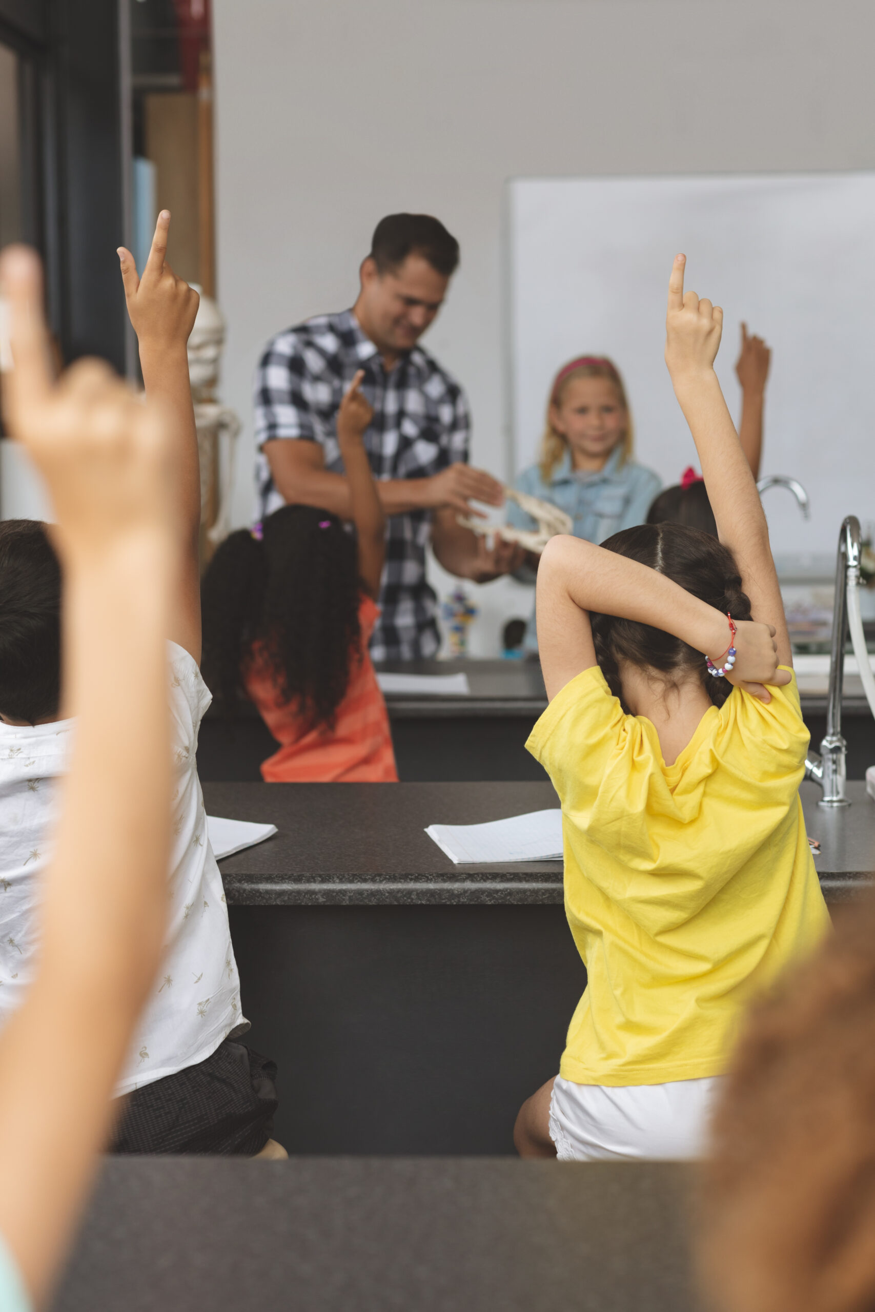 Des enfant lèvent la main en classe